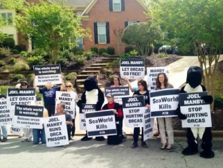 A group of people holding signs in front of a house to protest SeaWorld